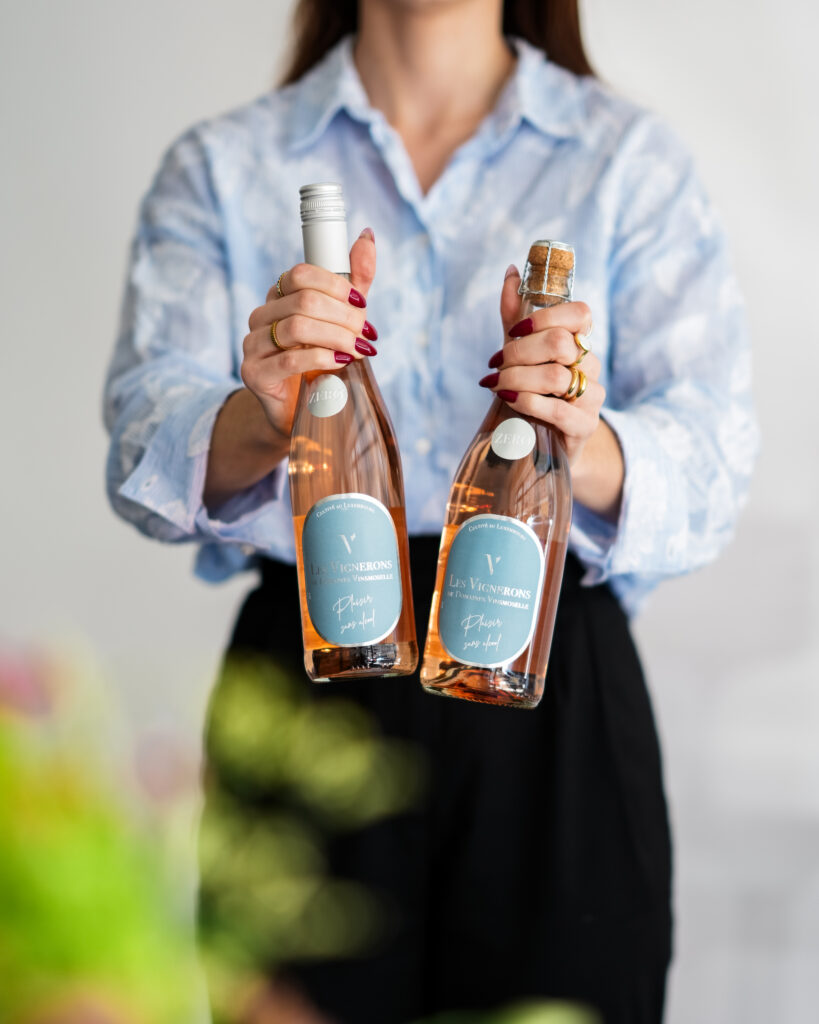 Domaines Vinsmoselle, femme qui tient deux bouteilles de rosé sans alcool