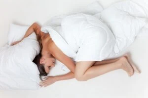 dormir, femme qui dort en formant un rond, elle dort dans des draps blancs