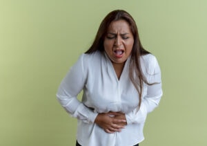 Laboratoires Boiron, règles douloureuses, femme qui se tient le ventre sur fond vert, endométriose